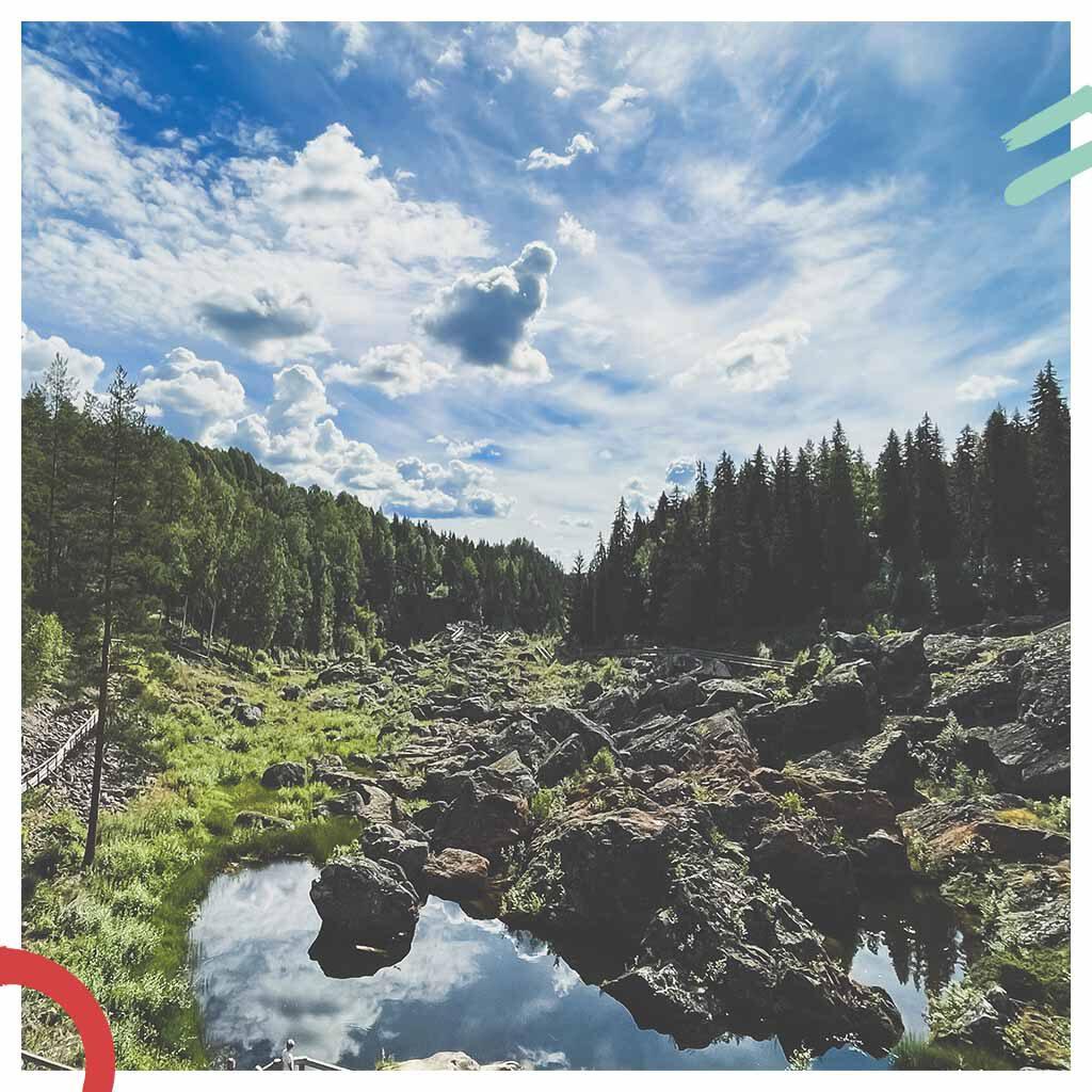 Naturhalt Ausblick auf einen blauen Himmel mit Wolken, Wälder und einen ausgetrockneten Fluß mit großen Steinen in der Natur